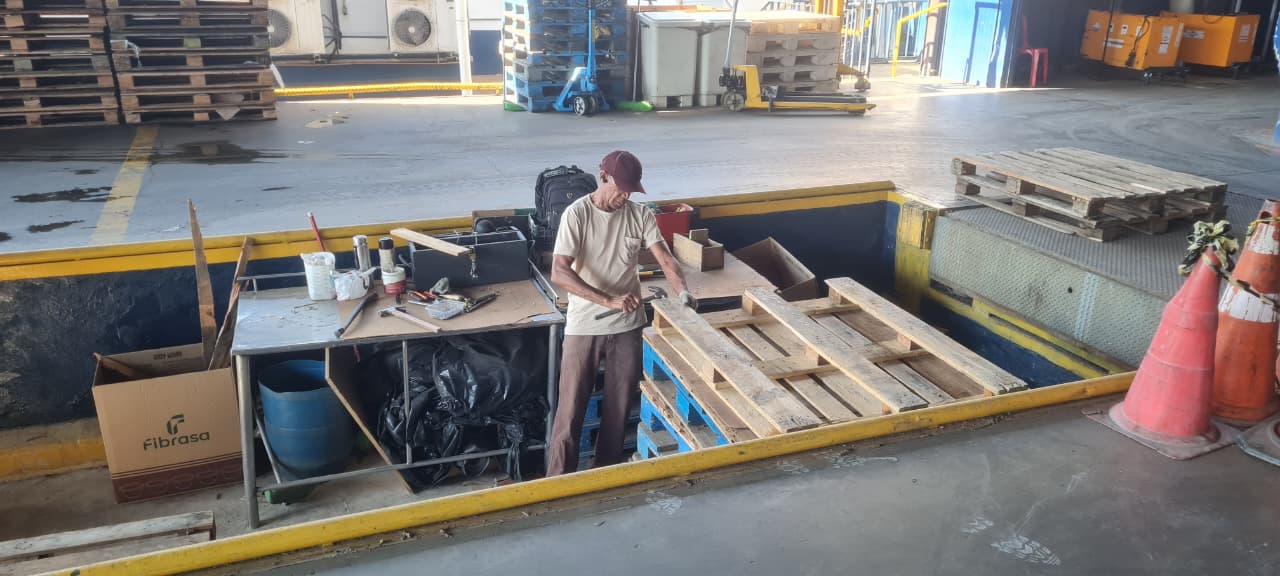 Paleteira manual transportando pilha de pallets na área de carga
